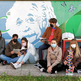 ragazzi liceo seduti davanti murales Einstein